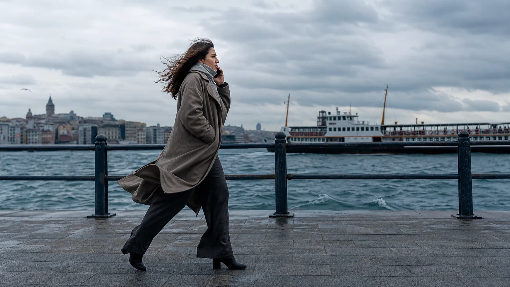 A woman making a relaxed phone call while walking along a sunny waterfront path