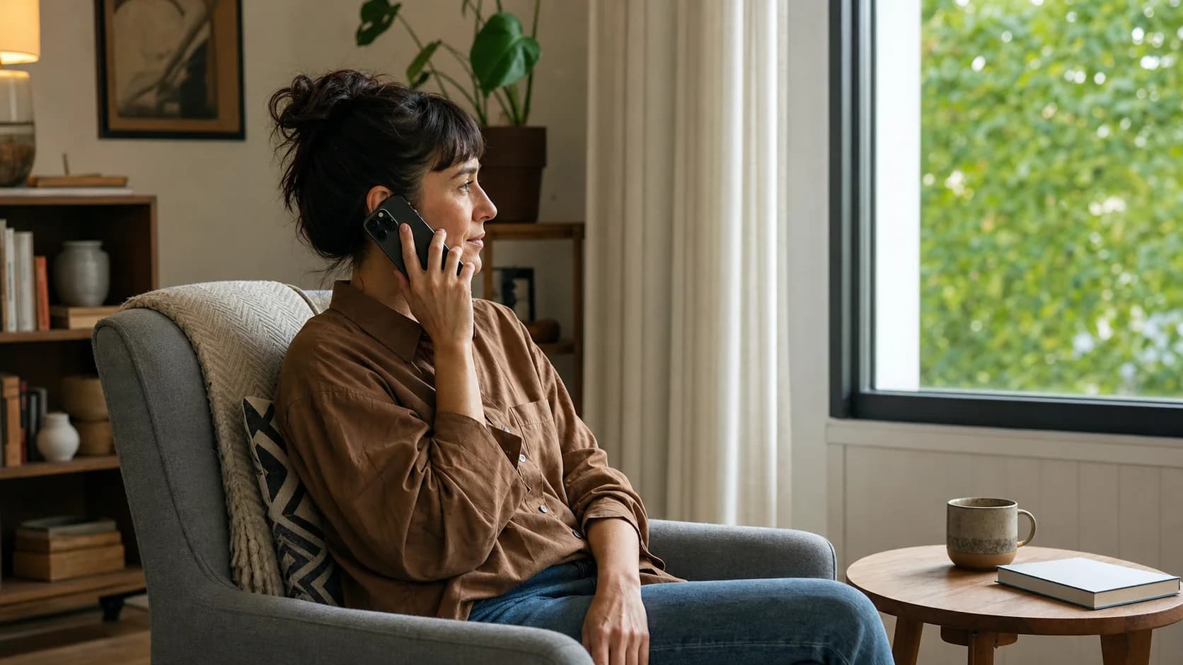 A woman making a quiet personal phone call from an apartment armchair