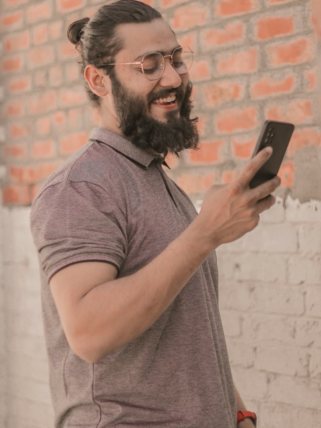 Man with a beard and glasses smiling at a message on his phone