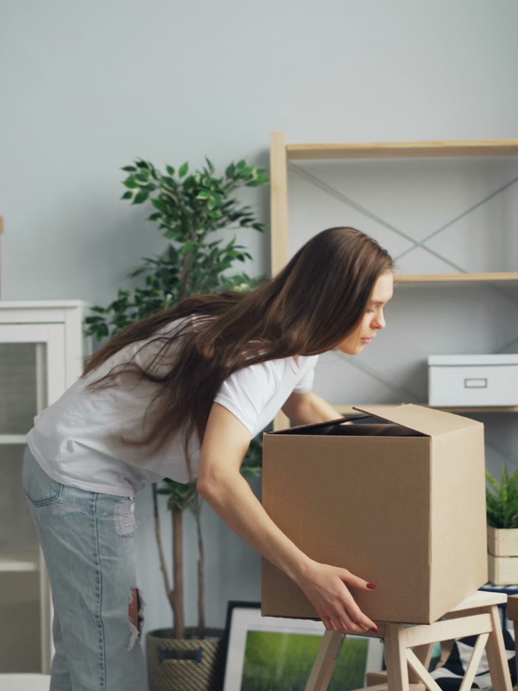 Woman at home packing an item into a cardboard box