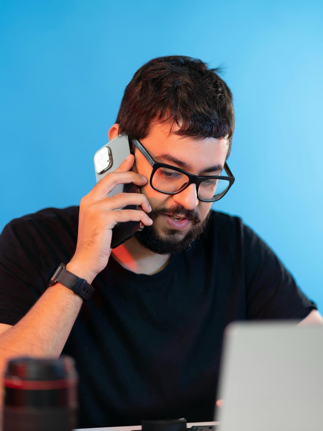 Man in glasses on a phone call at his laptop